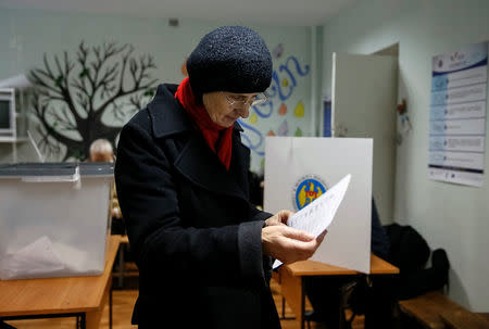 A woman reads her ballot during a presidential election at a polling station in Chisinau, Moldova, October 30, 2016. REUTERS/Gleb Garanich
