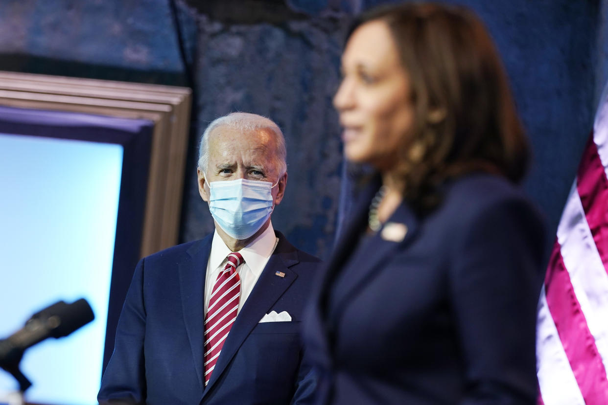 President-elect Joe Biden listens as Vice President-elect Kamala Harris, speaks about economic recovery at The Queen theater, Monday, Nov. 16, 2020, in Wilmington, Del. (AP Photo/Andrew Harnik)