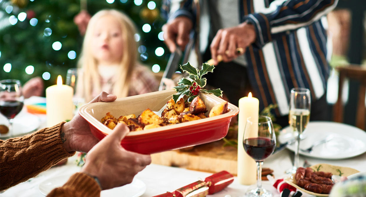 Family sat round a Christmas dinner, handing around food. (Getty Images)