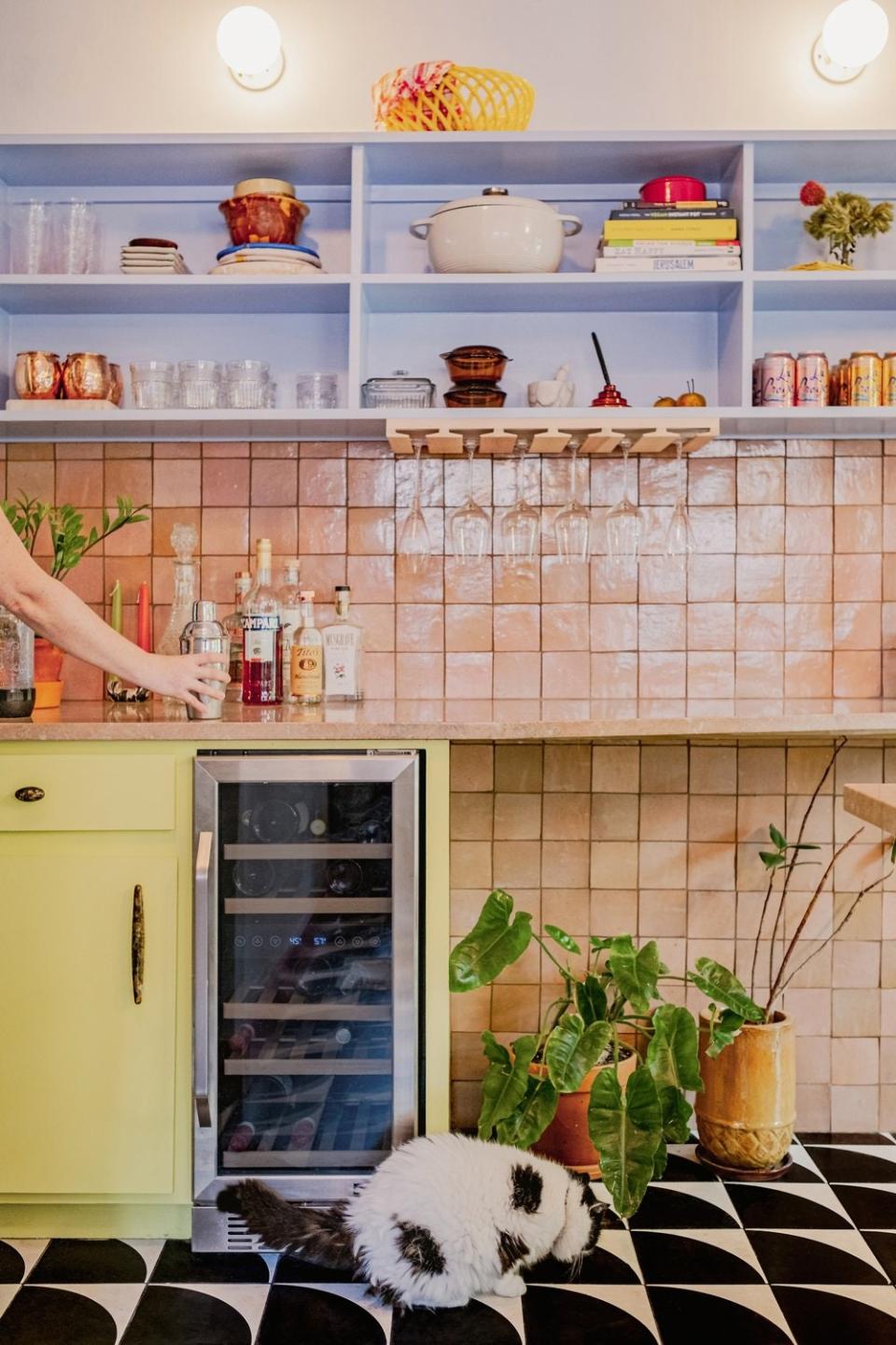 Black-and-white tiles form a graphic contrast to the pastel hues seen in the backsplash and cabinetry.