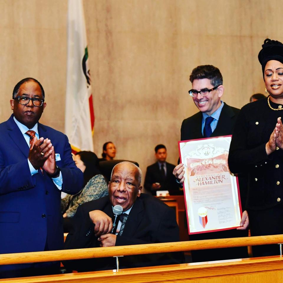 Alexander Hamilton receives a proclamation from the L.A. County Board of Supervisors, accompanied by film producer Alan Elliott and Hamilton’s wife, Alicia - Credit: Martin Zamora