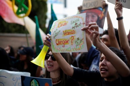 Demonstrators hold signs during a protest to demand more Amazon rainforest protection at the embassy of Brazil in Quito
