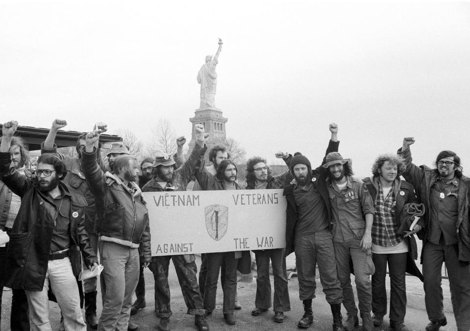 FILE - Members of the Vietnam Veterans Against the War raise clenched fists after ending their 40-hour occupation of State of Liberty, which can be seen behind them, Dec. 28, 1971. They’re hallmarks of American history: protests, rallies, sit-ins, marches, disruptions. They date from the early days of what would become the United States to the sights and sounds currently echoing across the landscapes of the nation’s colleges and universities. (AP Photo/Anthony Camerano, File)