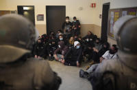 Rap singer Pablo Hasél, background, is surrounded by his supporters as police officers try to arrest him at the University of Lleida, Spain, Tuesday, Feb. 16, 2021. A rapper in Spain and dozens of his supporters have locked themselves inside a university building in the artist's latest attempt to avoid a prison sentence for insulting the monarchy and praising terrorism. (AP Photo/Joan Mateu)