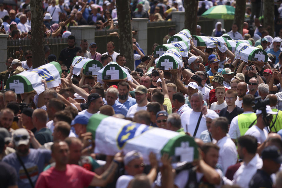 Bosnian muslim men pray carry the coffins containing the remains of 30 newly identified victims of the Srebrenica Genocide in Potocari, Bosnia, Tuesday, July 11, 2023. Thousands gather in the eastern Bosnian town of Srebrenica to commemorate the 28th anniversary on Monday of Europe's only acknowledged genocide since World War II. (AP Photo/Armin Durgut)