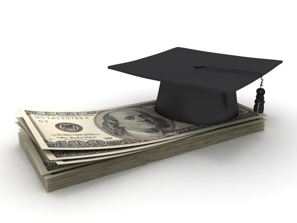 Dollars stacked under a graduation cap