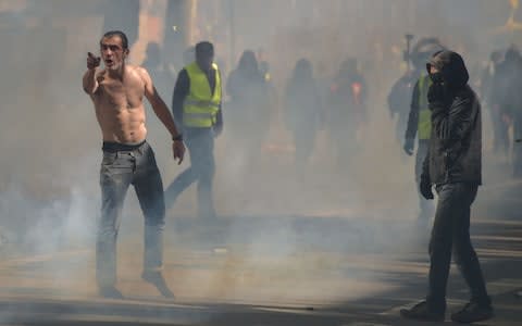 "Yellow vests" protesters stand amid tear gas smokes as during a demonstration  - Credit: &nbsp;PASCAL PAVANI/AFP