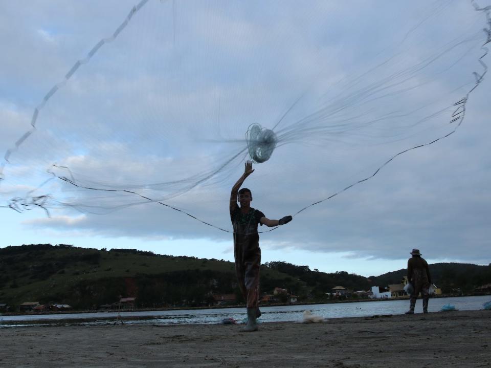 A boy throws a net towrads the camera. It forms a neat circle in the air.