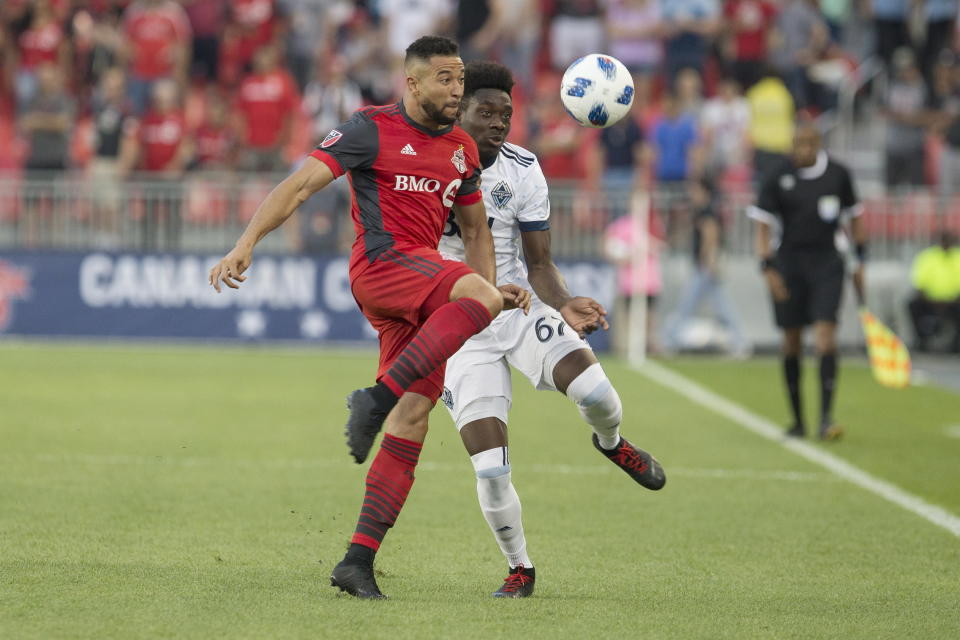 Toronto FC's Justin Morrow, left, and Vancouver Whitecaps' Alphonso Davies vie for control of the ball during the first half in the second leg of the Canadian soccer championship final, Wednesday, Aug. 15, 2018, in Toronto. (Chris Young/The Canadian Press via AP)