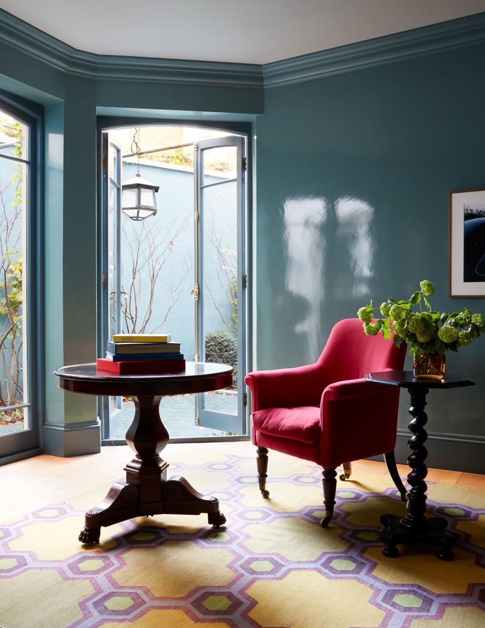 A reading nook in the garden room pairs the rich texture of a reupholstered chair from Dean Antiques with Will Foster Studios’ bespoke lacquer paint treatment.