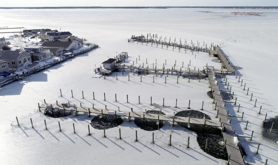 After days of freezing temperatures, the water surrounding the dock at the Ocean Beach Marina is iced over Monday afternoon, January 31, 2021.  The circle of clear water is created by an ice suppression system that keeps it moving.