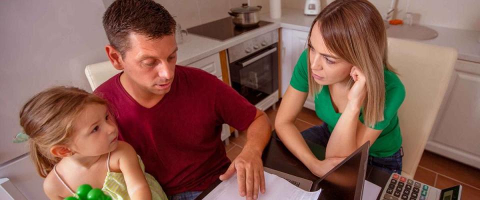 busy family - young couple with daughter planning home budget