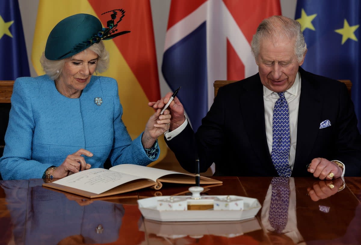 Charles hands over a pen to Camilla to sign the guest book at the presidential Bellevue Palace in Berlin (AFP via Getty Images)