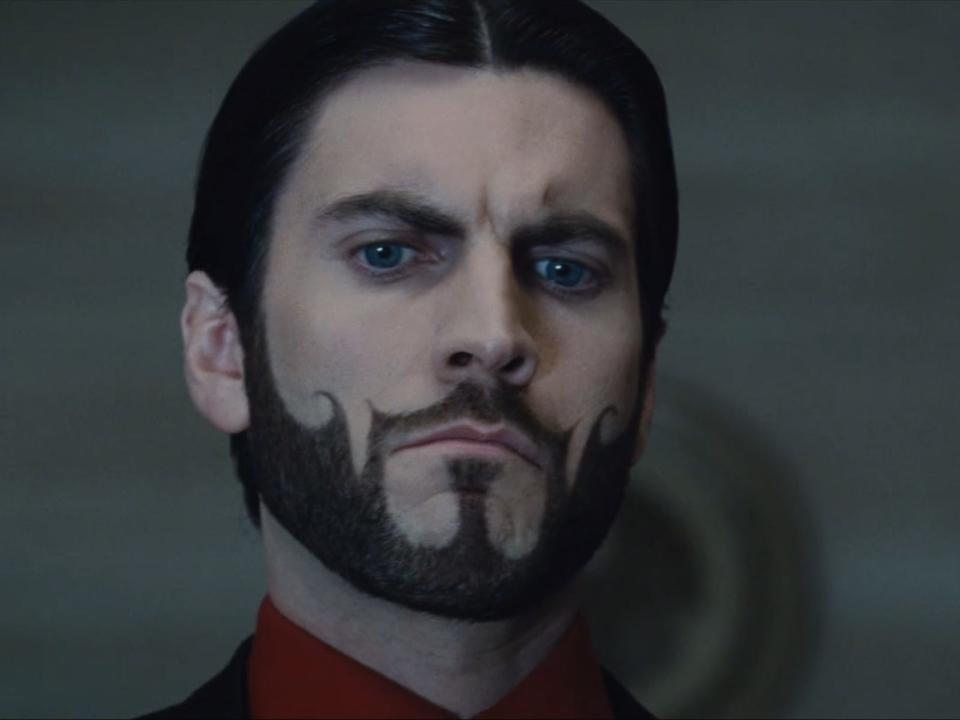seneca crane looking questioningly at a bowl of nightlock berries in the hunger games