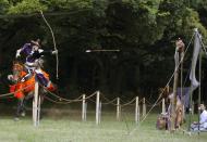 An arrow flies through the air to its target as President Barack Obama watches a Yabusame or horseback archery demonstration as he tours Meiji Shrine in Tokyo, Thursday, April 24, 2014. Showing solidarity with Japan, Obama affirmed Thursday that the U.S. would be obligated to defend Tokyo in a confrontation with Beijing over a set of disputed islands, but urged all sides to resolve the long-running dispute peacefully. (AP Photo/Carolyn Kaster)