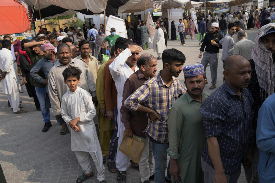 People gather and wait their turn to get a free sack of wheat flour at a distribution point, in Lahore, Pakistan, Thursday, March 30, 2023. Government is providing free flour to deserving and poor families during the Muslim's holy month of Ramadan due to high inflation in the country. (AP Photo/K.M. Chaudary)