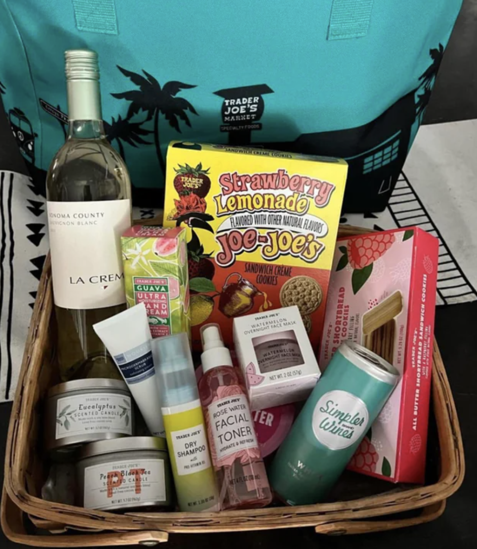 A woman is showing off the gift basket one of her friends dropped off for her