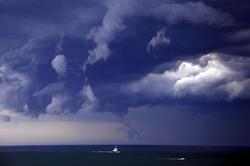 FILE PHOTO: Boats head into shore as storm clouds move along the coast towards the city of Sydney, Australia