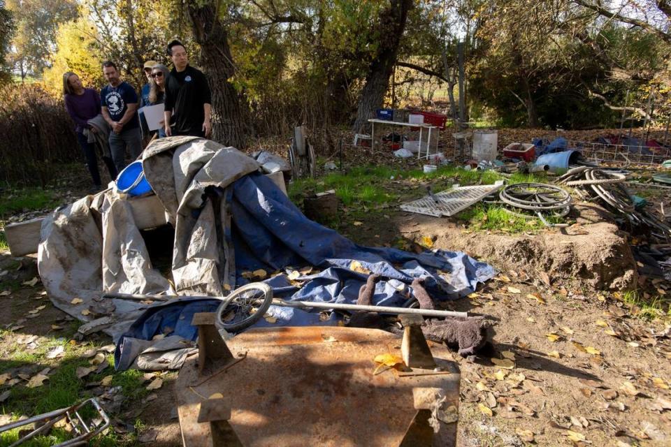 Sacramento County District Attorney Thien Ho observes an abandoned homeless encampment, littered with debris after the person died, during a tour with the River City Waterway Alliance at Steelhead Creek in Sacramento on Tuesday.