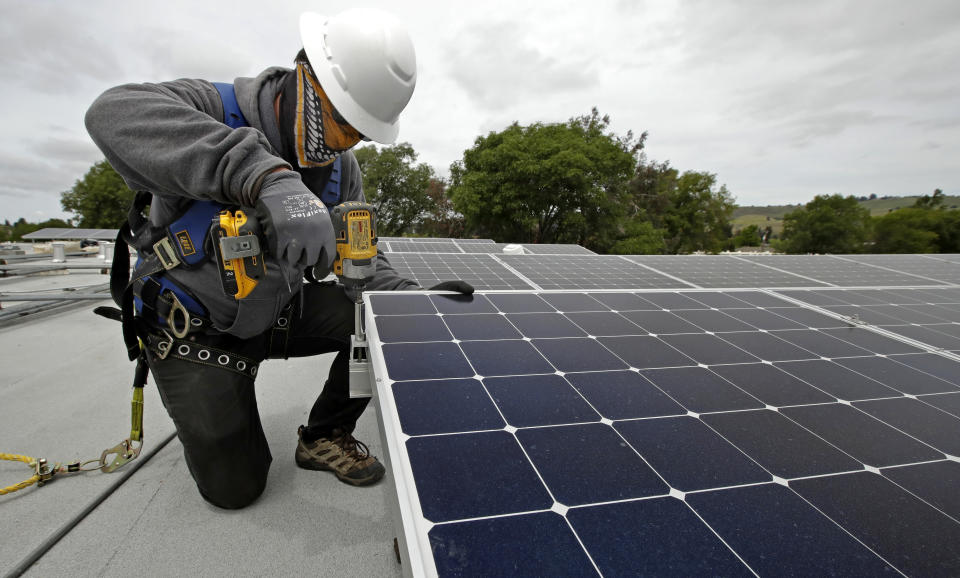FILE - Gen Nashimoto, of Luminalt, installs solar panels in Hayward, Calif., on Wednesday, April 29, 2020. California air regulators will take public comment Thursday, June 23, 2022, on a plane to slash fossil fuel use and reach carbon neutrality by 2045. (AP Photo/Ben Margot, File)
