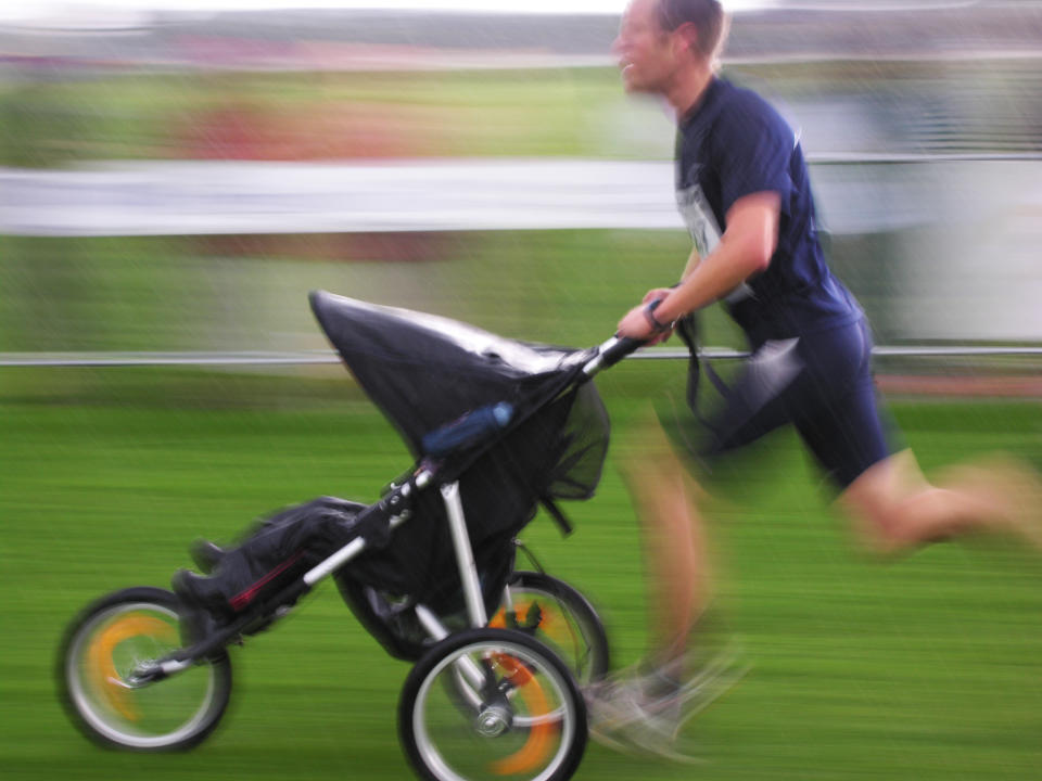 Person running and pushing a baby stroller in a blurred motion, indicating speed
