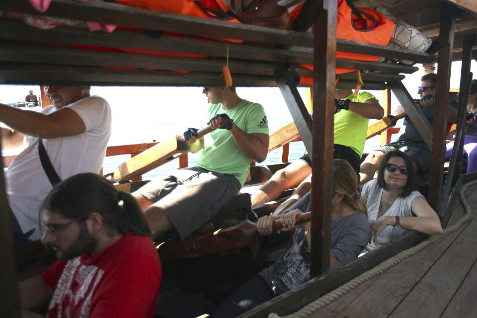 In this Sunday, Sept. 16, 2018 photo, visitors row the Olympias, replica of an ancient galley, at Saronic gulf in southern Athens. The 37-meter (121-foot) wooden vessel moored off southern Athens is an experimental reconstruction of the trireme, the sleek ancient Greek warship that halted a Persian invasion of Europe and ruled the Mediterranean for centuries. Every summer, visitors can get a whiff of life in the galleys 2,500 years ago by joining the crew of the Olympias, and work up a sweat rowing it. (AP Photo/Thanassis Stavrakis)