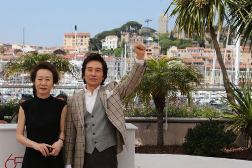 South Korean actor Baek Yoon-sik (R) raises his fist while posing with South Korean actress Youn Yuh-jung during the photocall of "Do-Nui Mat" (The Taste of Money) presented in competition at the 65th Cannes film festival. A sex-infused expose of rampant corruption among the super-rich in today's South Korea premiered, but the director slammed the Western view of Asian cinema