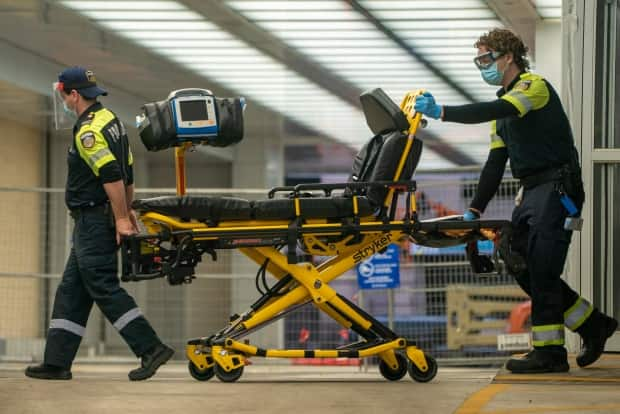 Two paramedics push a gurney out of Mt. Sinai Hospital's emergency entrance in Toronto after dropping off a patient on March 26, 2021. (Sam Nar/CBC - image credit)