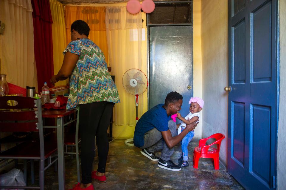Verty plays with his 1-year-old daughter while his wife Saint Jean fixes the house in Port-au-Prince, Haiti, on Aug. 25, 2020. The Trump administration had sharply increased its use of hotels to detain immigrant children before expelling them from the United States during the coronavirus pandemic. Verty says government contractors at a hotel where he was detained gave his family, including his daughter, cups of ice to eat to pass temperature checks prior to their deportation flight, even though they had tested negative for COVID-19.