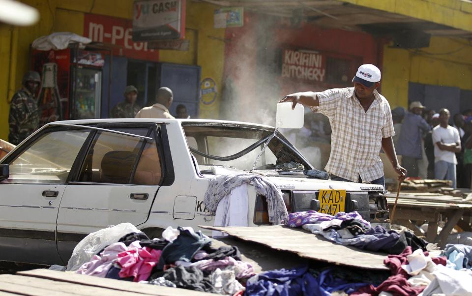 A trader attempts to extinguish fire inside a car at the scene of a twin explosion at the Gikomba open-air market for second hand clothes in Kenya's capital Nairobi May 16, 2014. At least four people were killed on Friday in two explosions in the Kenyan capital Nairobi, the country's National Disaster Operations Centre (NDOC) said. (REUTERS/Thomas Mukoya)