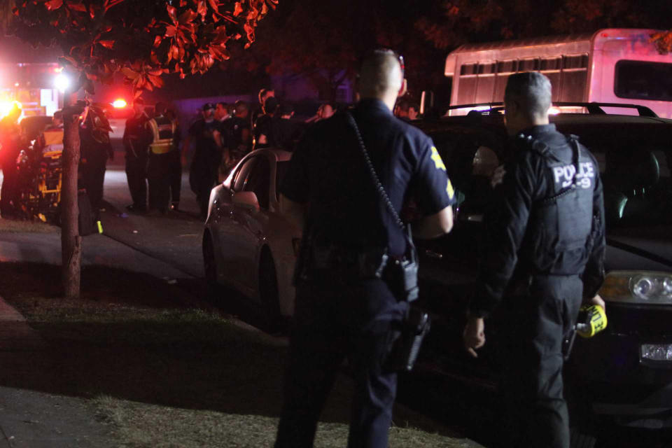 Police and emergency personnel work at the scene of a shooting at a backyard party, Sunday, Nov. 17, 2019, in southeast Fresno, Calif. Multiple people were shot and at least four of them were killed Sunday at a party in Fresno when suspects sneaked into the backyard and fired into the crowd, police said. (Larry Valenzuela/The Fresno Bee via AP)