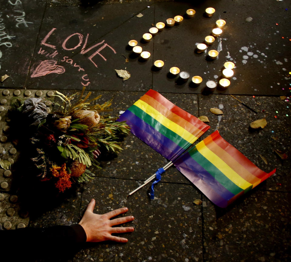 A man touches the ground next to rainbow flags during a candlelight vigil for the victims of the Pulse Nightclub shooting in Orlando, Florida, at Newtown Neighbourhood Centre on June 13, 2016 in Sydney, Australia.&nbsp;