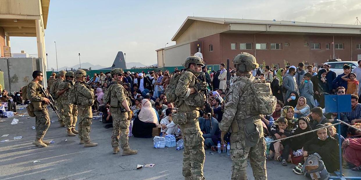 US soldiers stand in front of a crowd of Afghan people.