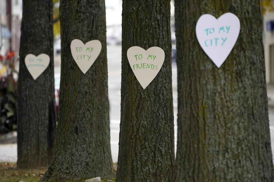 Heart-shaped signs on four trees, with messages saying "to my city" and "to my friends."
