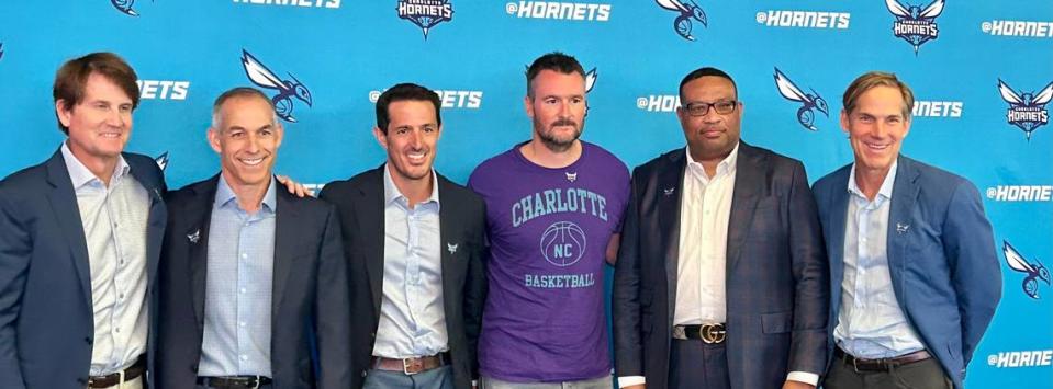 Most of the new ownership group of the Charlotte Hornets poses for a picture on Aug. 3, 2023, at the Spectrum Center in Charlotte, N.C. Second from left is Rick Schnall. Third from left is Gabe Plotkin. The two have a controlling interest in the Hornets. The other four people pictured are minority owners, including country music star Eric Church (in purple T-shirt).