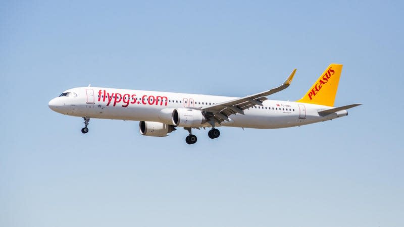 A white narrow-body airliner with a yellow tailfin preparing to land