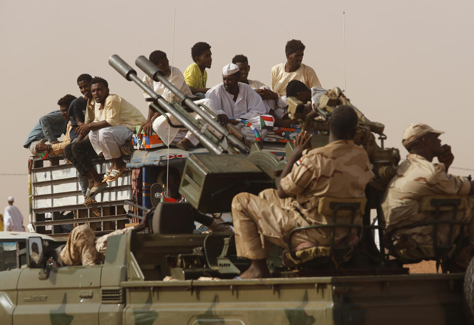 Sudanese supporters of Gen. Mohammed Hamdan Dagalo, the deputy head of the military council, sit on the top of a truck in front of soldiers from the Rapid Support Forces unit, during a military-backed tribe's rally, in the East Nile province, Sudan, Saturday, June 22, 2019. Sudan's protest leaders say they are meeting with an Ethiopian envoy over proposals to resume negotiations with the ruling military council. (AP Photo/Hussein Malla)