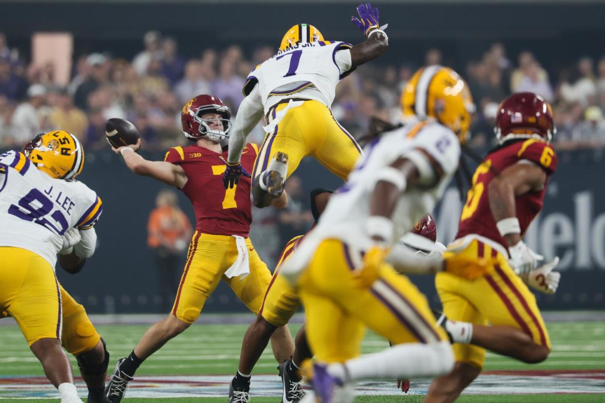 LSU Tigers cornerback Ashton Stamps leaps over a lineman in pursuit of USC Trojans quarterback Miller Moss.