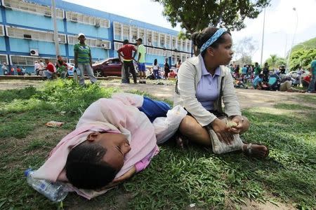 People lay on the grass outside a health center as they wait to get treatment for malaria, in San Felix, Venezuela November 3, 2017. REUTERS/William Urdaneta/Files