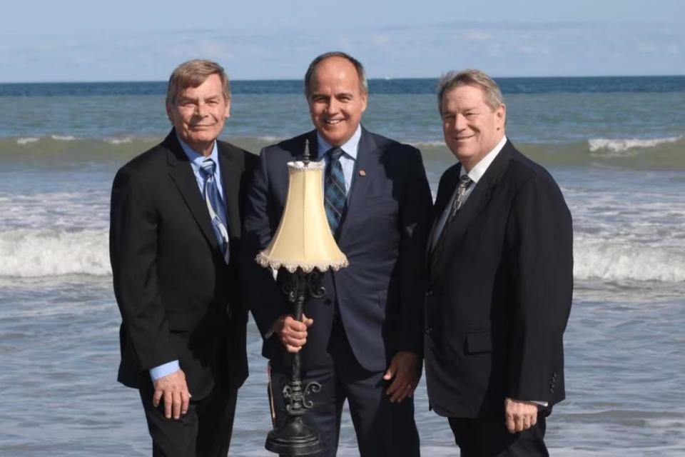 Former NB Power CEO Gaëtan Thomas, centre, poses with Joi Scientific executives Robert Koeneman, left, and Traver Kennedy on a beach in Cape Canaveral, Fla.,  NB Power spent $13 million on a failed attempt to make the company's plan to extract hydrogen from seawater work.