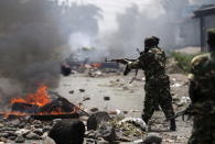 A soldier fires an AK-47 rifle during a protest against President Pierre Nkurunziza and his bid for a third term, in Bujumbura, Burundi, May 25, 2015. REUTERS/Goran Tomasevic