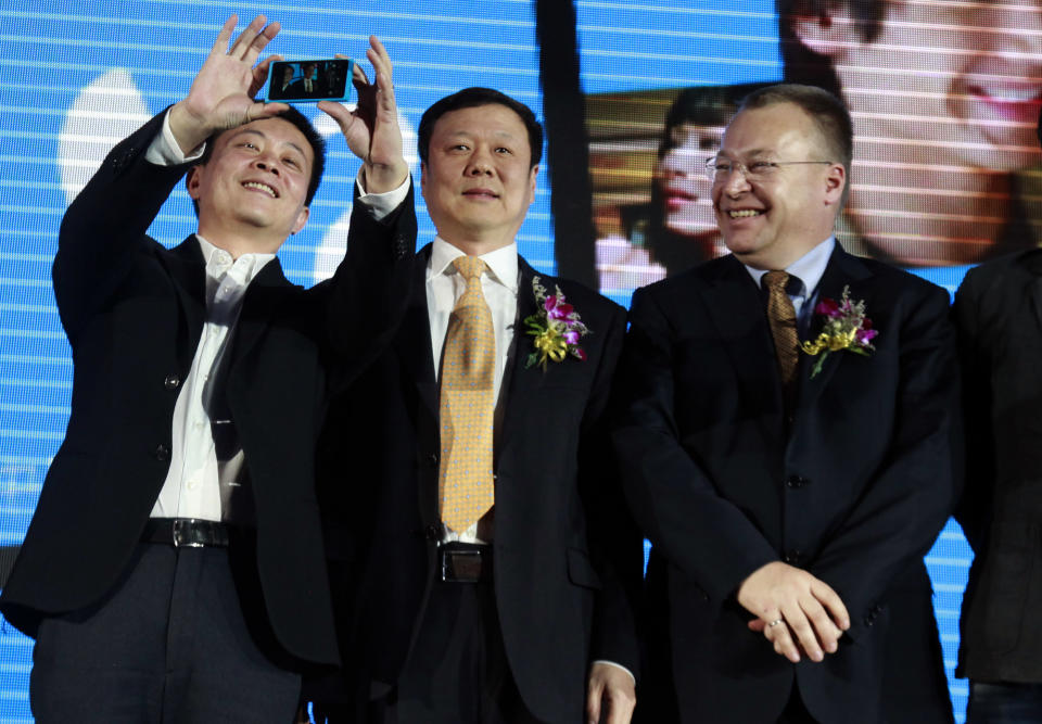 Nokia CEO Stephen Elop, right, smiles as Sina.com CEO Charles Chao, left, takes a photo of them and Wang Xiaochu, Chairman of China Telecoms, center, with Nokia's newly launched Lumia 800C smartphone in Beijing, China, Wednesday, March 28, 2012. Struggling cellphone maker Nokia launched its first smartphone design for China on Wednesday, looking to the world's biggest mobile market to help drive a turnaround.(AP Photo/Ng Han Guan)