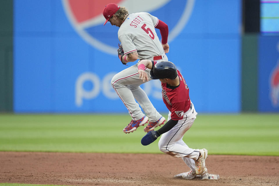 Philadelphia Phillies second baseman Bryson Stott (5) jumps out of the way of Cleveland Guardians' Steven Kwan, bottom, after forcing out Kwan at second base in the fourthinning of a baseball game Friday, July 21, 2023, in Cleveland. (AP Photo/Sue Ogrocki)