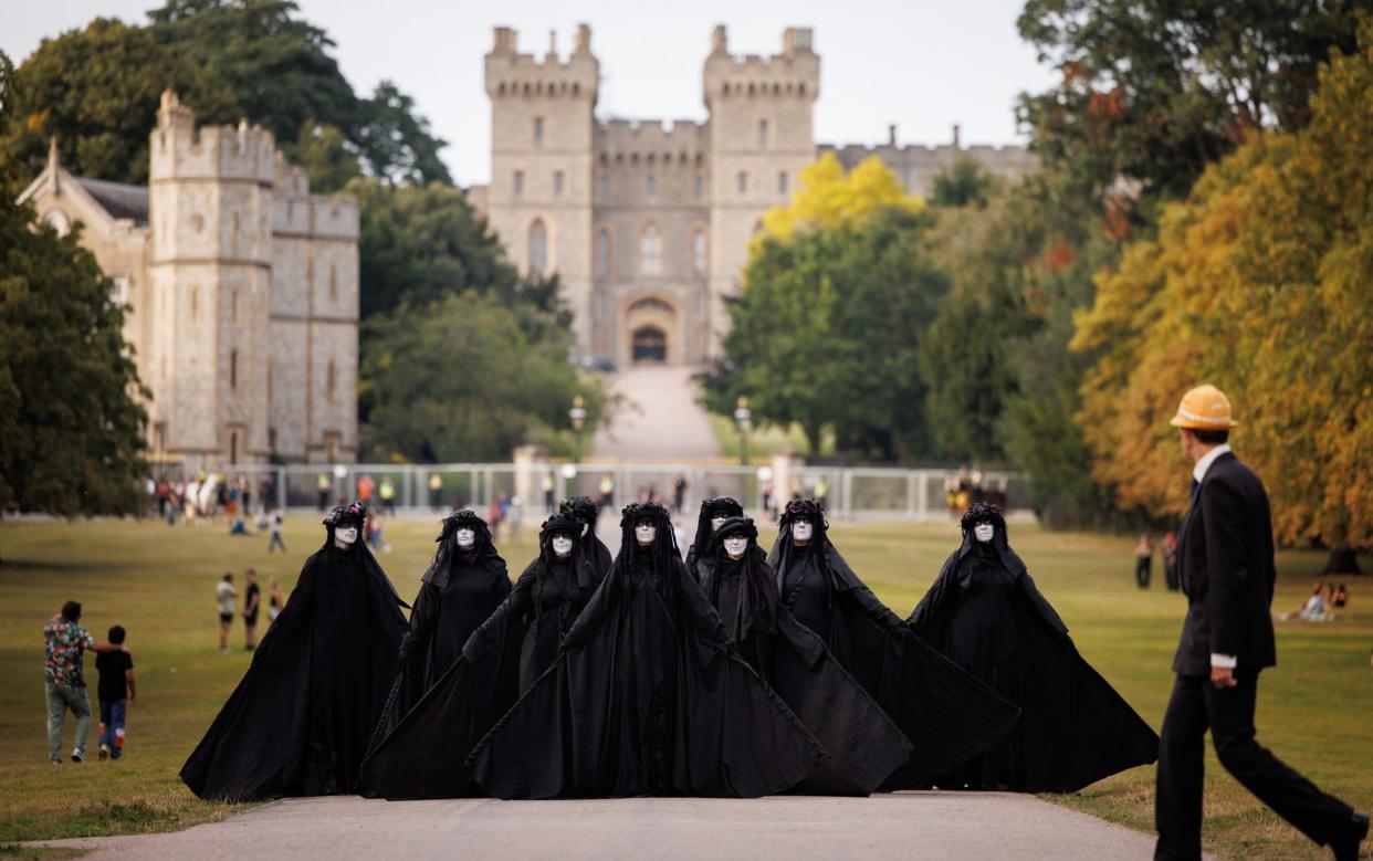 A symbolic oil slick composed of funereal figures dressed in black filed slowly to the castle gates on Friday