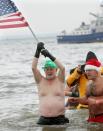 NEW YORK, NY - JANUARY 1: A man hoists a flag as he takes part in the Coney Island Polar Bear Club's New Year's Day swim on January 1, 2013 in the Coney Island neighborhood of the Brooklyn borough of New York City. The annual event attracts hundreds who brave the icy Atlantic waters and temperatures in the upper 30's as a way to celebrate the first day of the new year. (Photo by Monika Graff/Getty Images)