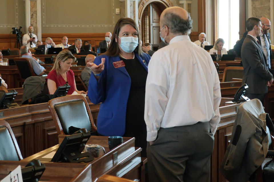 FILE - In this Wednesday, June 3, 2020 file photo, Kansas state Rep. Stephanie Clayton, left, D-Overland Park, confers with House Minority Leader Tom Sawyer, D-Wichita, during a break in the House chamber at the Statehouse in Topeka, Kan. The nation's ongoing battle against the coronavirus is dividing lawmakers along partisan lines in state Capitols. In some cases, the divisions can be seen simply by looking at lawmakers' faces. In some legislative chambers, many Democrats are wearing masks during debates while many Republicans are not. (AP Photo/John Hanna, File)