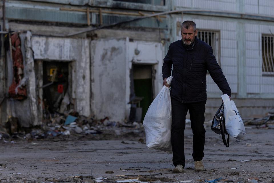 A local resident walks out of his damaged apartment with belongings after yesterday's missile strike by Russia (REUTERS)