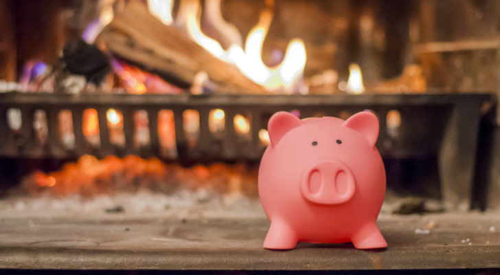 a pink piggy bank placed on the hearth of a cozy lit fireplace