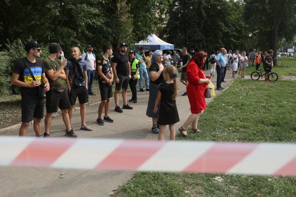 Local residents look at the rescuers works outside a nine-storey residential building partially destroyed as a result of Russian missiles strike in Kryvyi Rig on 31 July (AFP via Getty Images)