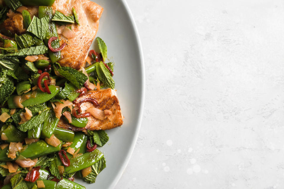 This image released by Milk Street shows a recipe for salmon with chilies, pickled ginger and snap peas. (Milk Street via AP)